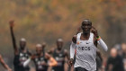 Eliud Kipchoge approaches the finish line, with his pacemakers celebrating behind. 