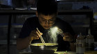 A man uses his smartphone to light up his breakfast during a blackout in Shenyang in north-eastern China.