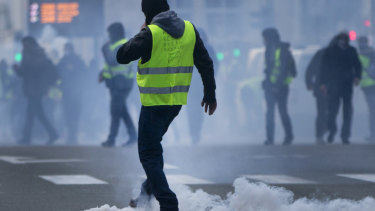 A demonstrator kicks a tear gas container back at police during a protest of the yellow jackets.