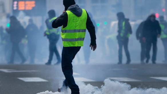 A demonstrator kicks a tear gas container back at police during a protest of the yellow jackets.
