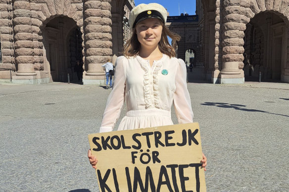 Thunberg with a sign reading in Swedish “School strike for the Climate” while wearing the cap in Stockholm on Friday that high school students typically wear in Sweden upon graduation.