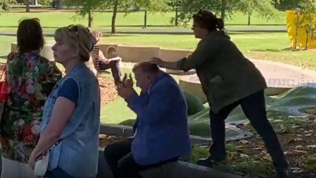 A woman smashes an egg on Craig Kelly’s head in a Melbourne park.