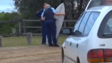 Police examine the boy's damaged surfboard.