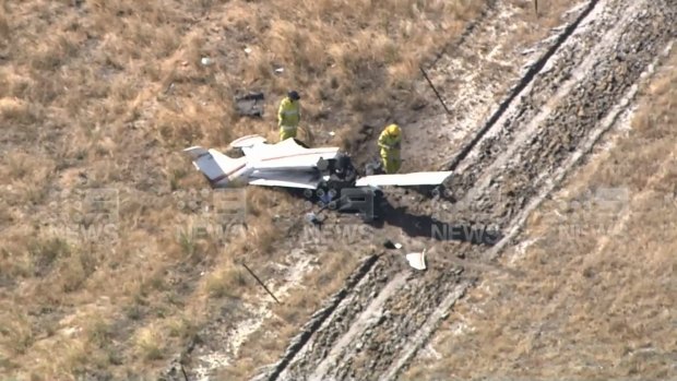 Emergency services workers examine a light plane which crashed in Perth's south on Monday, leaving one person dead.