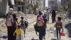 Palestinian women and their children walk though destruction in the wake of an Israeli air and ground offensive in Jebaliya in May, 2024.