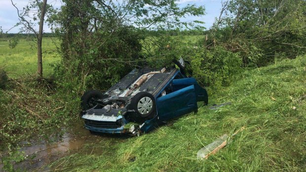 A car lies upside down in a ditch following a tornado in Franklin, Texas. 