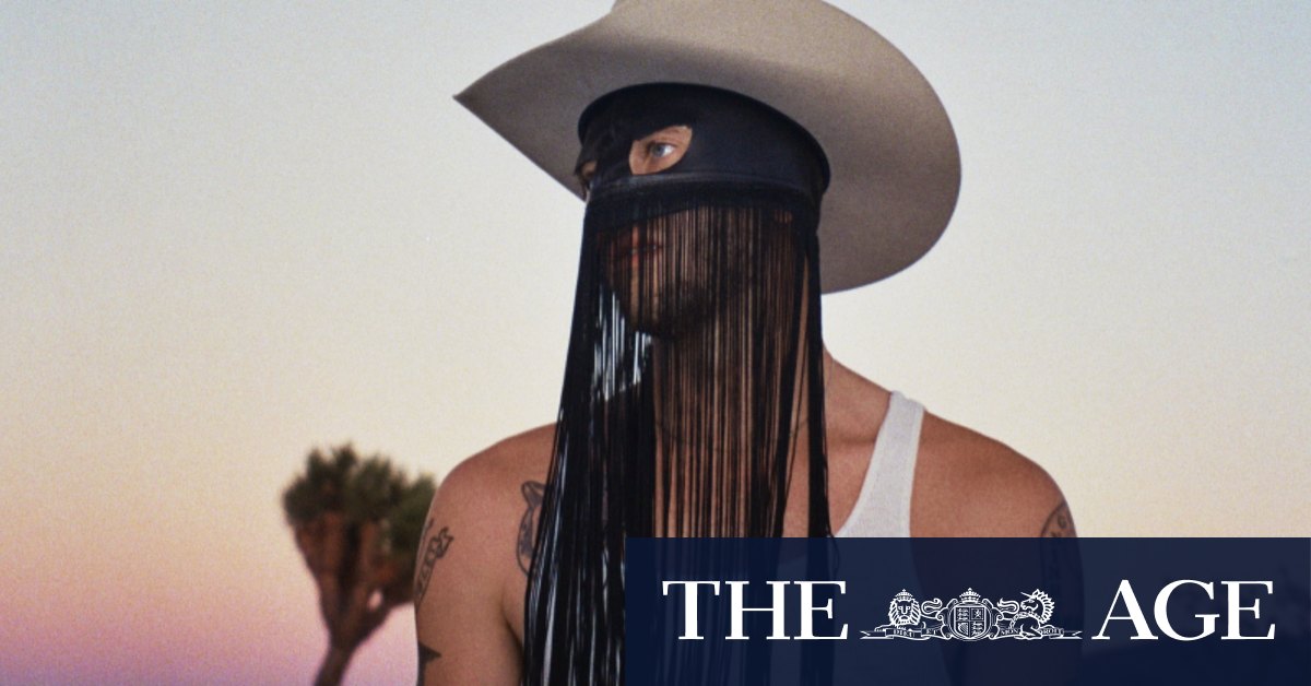Orville Peck behind the man in the fringed mask