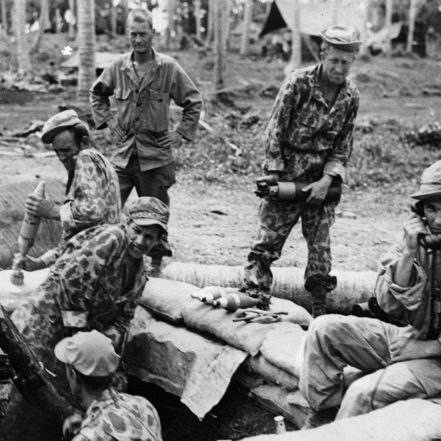 During World War II, soldiers fire a camouflaged gun during a barrage in the Solomon Islands.