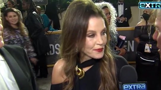 Lisa Marie Presley being interviewed by Extra on the red carpet at the 2023 Golden Globes. She appeared to slur her words and asked to be helped to stay steady by Jerry Schilling.