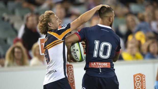 The Brumbies' Joe Powell and the Rebels' Quade Cooper exchange pats on the head as they fight for the ball.