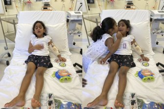 Sister Kopika comforts Tharnicaa with in hospital on Christmas Island this week before she was evacuated to a Perth hospital.