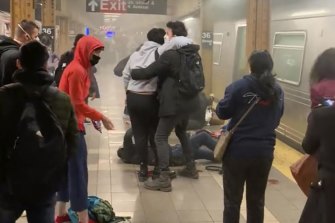 A person is assisted outside a subway car in the Brooklyn borough of New York after a shooting.