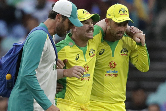 David Warner is helped from the field by David Beakley and Glenn Maxwell during the second ODI.