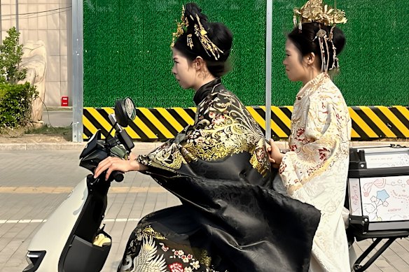 Duas jovens em trajes tradicionais chineses em uma scooter elétrica no distrito de Dongcheng, no leste de Pequim.