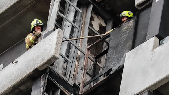 Firefighters remove cladding from the Spencer Street apartment building.