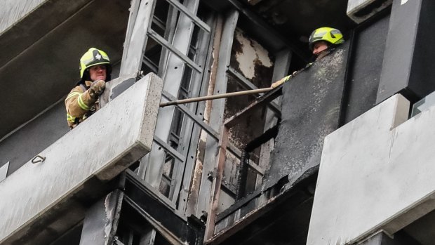 Firefighters remove cladding from the Spencer Street apartment building.