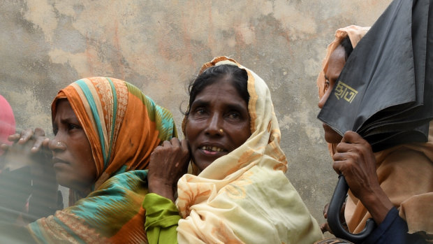 Rohingya refugee women wait in their line as the men in their line run past for a meal provided by a Turkish aid agency.