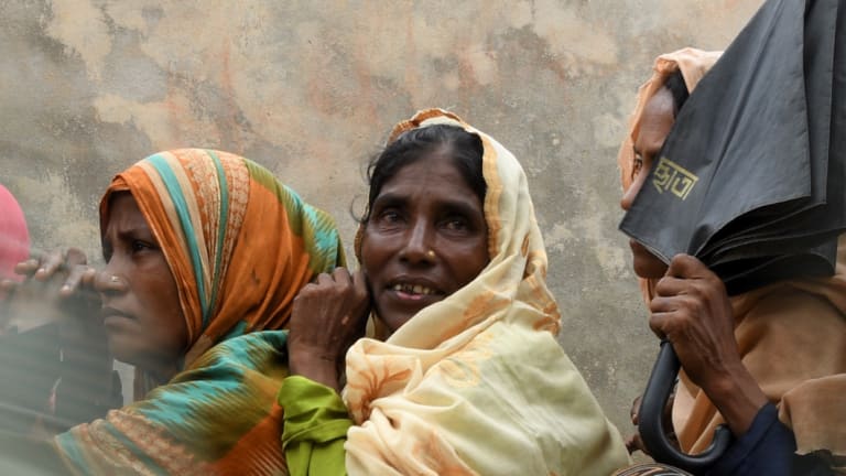 Rohingya refugee women wait in their line as the men in their line run past for a meal provided by a Turkish aid agency.