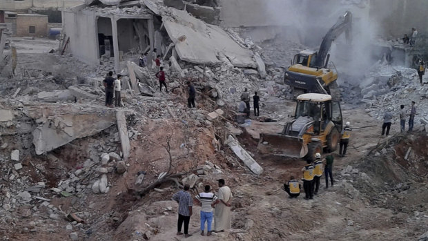White Helmets civil defence workers and civilians inspecting damaged buildings after airstrikes hit in the village of Zardana, in Idlib province, on Friday.