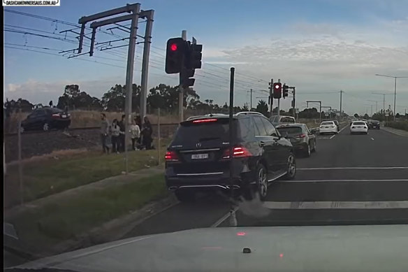 Onlookers frantically attempt to warn the driver as the train hurtles towards the car on Thursday afternoon.