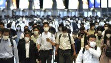 Commuters wearing face masks walk in a passageway during a rush hour at Shinagawa Station in Tokyo. 
