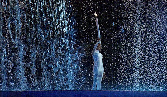 As the cauldron rises, Cathy Freeman carries the Olympic flame at the Sydney 2000 Games.