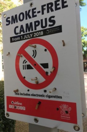 The smoking-ban sign at UQ vandalised with cigarette butts.