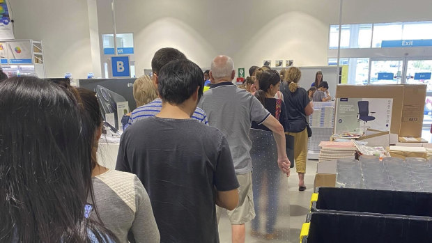 People line up at Officeworks in Osborne Park, with many preparing to begin working from home over coming days.