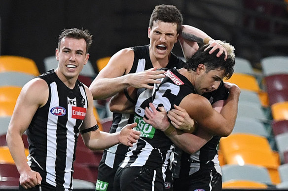 Josh Daicos is mobbed after kicking the sealer for the Magpies.