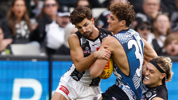 Charlie Curnow of the Blues is tackled by Josh Daicos of the Magpies and Darcy Moore of the Magpies.
