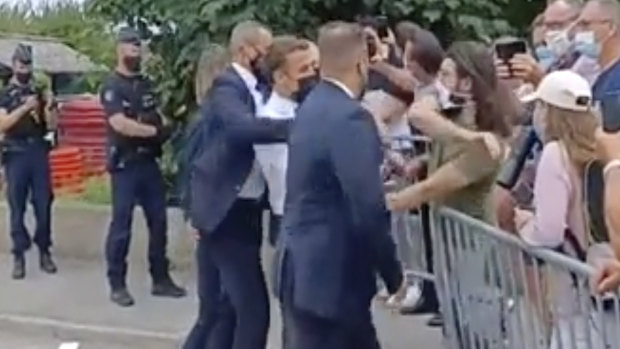 In this grab taken from video French President Emmanuel Macron, centre, is slapped by a man, in green T-shirt, during a visit to Tain-l’Hermitage, on Tuesday.