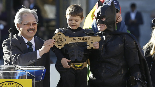 Miles Scott, dressed as Batkid, stands next to Batman as he receives the key to the city from San Francisco mayor Ed Lee at a rally outside City Hall in San Francisco in November 2013. 