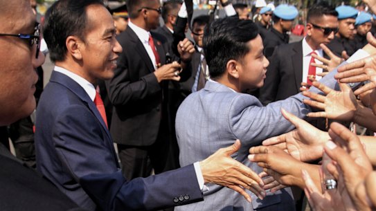 Indonesian President Joko Widodo, left, and his son, Gibran Rakabuming Raka, centre, greet supporters in 2019. A move to allow Gibran to run for president at age 36 was blocked by a court on Monday.