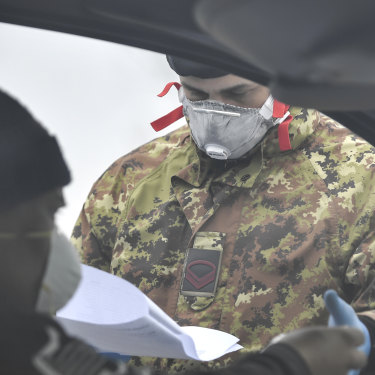 An Italian Army soldier checks paperwork at a cordon in Italy's north.