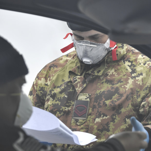 An Italian Army soldier checks paperwork at a cordon in Italy's north.
