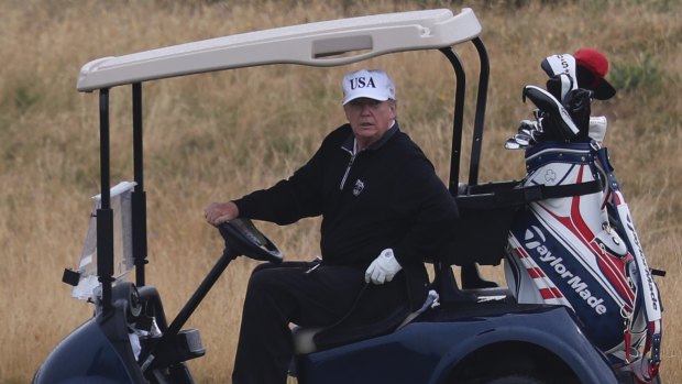 Donald Trump drives a golf buggy on his golf course in Turnberry, Scotland.