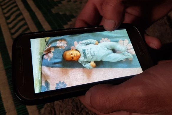 'Abu Hazem' cradles a photograph of his seven-month-old son who froze to death in his sleep in February.