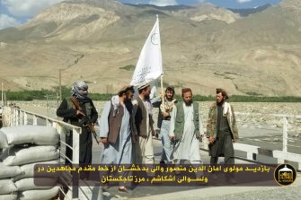 Taliban militants wave the insurgent groupâ€™s flag at the bridge on Ishkashim acting as a border crossing between Afghanistan and Tajikistan. 