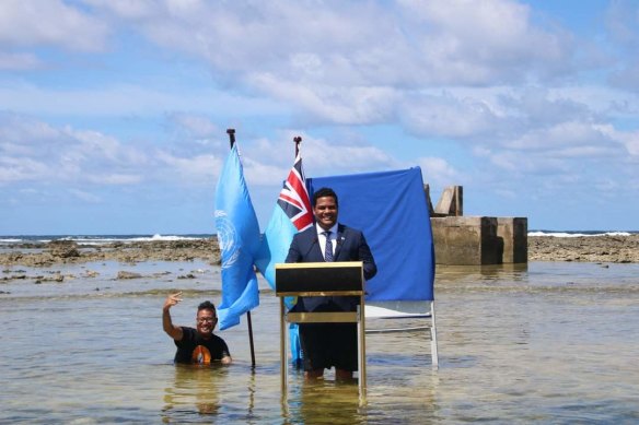 Министр иностранных дел Тувалу Саймон Кофе обращается к COP26, стоя в морской воде, которая угрожает его островному государству.
