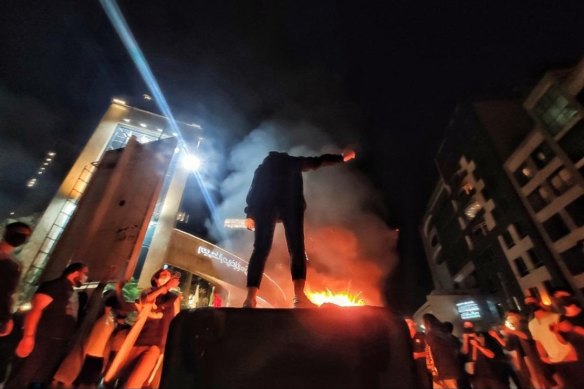 An Iranian woman stands defiantly above her burning headscarf.