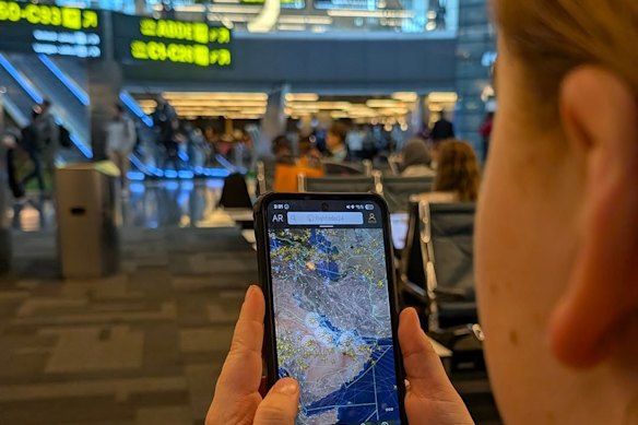 Matilda Milton watches the plane tracker in Doha airport after being stranded there.