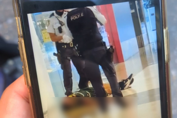 Two police officers stand near a suspected offender.