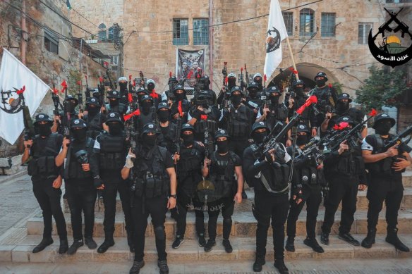 Lions’ Den fighters in their customary black uniforms with red ribbons tied around their rifle barrels.