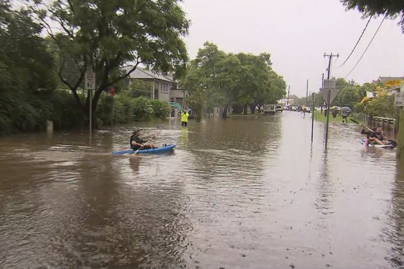 People kayaking through flooded Penrith streets.