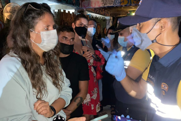 Thai immigration officers talk to people at a bar on Koh Phangan island after 89 foreigners were arrested.