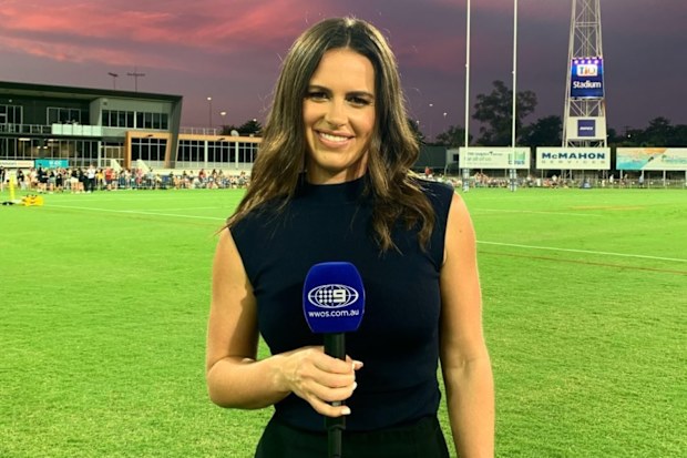Danika Mason standing on a sporting field holding a microphone.