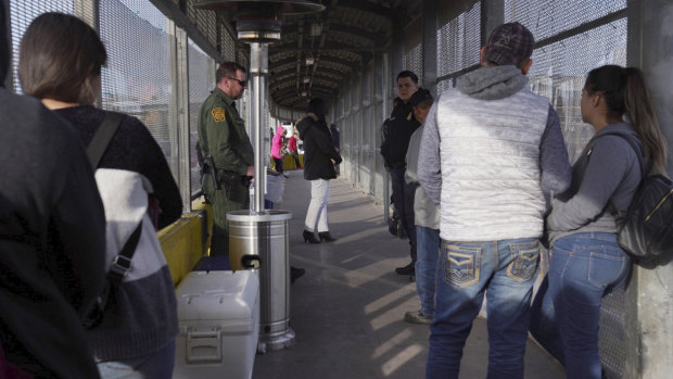 Border agents oversee the port of entry at the Gateway International Bridge, while people wait in line to cross into the US.