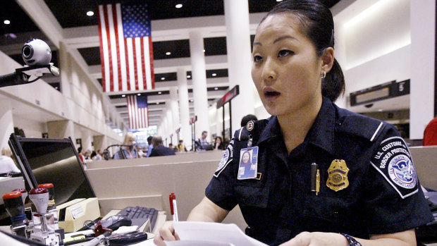 A US Customs and Border Protection officer checks the passport and paperwork of a visitor at Los Angeles International Airport.