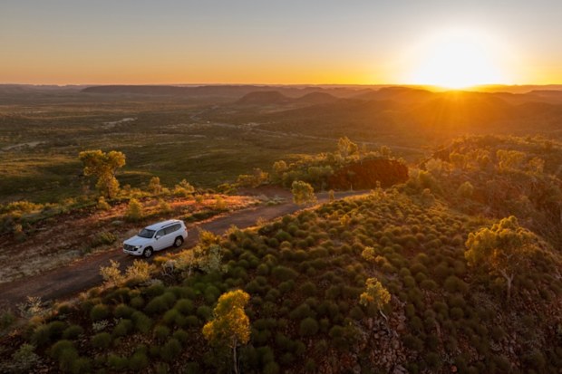 A car driving through the outback at sunset