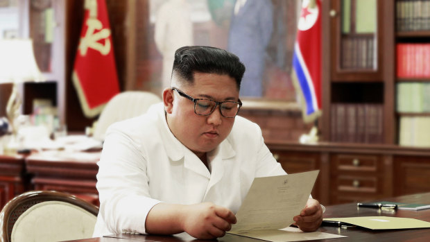 In a photo provided by the North Korean government, leader Kim Jong Un reads a letter said to be from US President Donald Trump. 